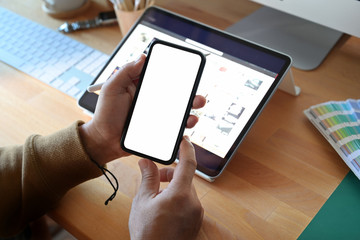 Top view of man holding blank screen mobile smartphone on office wood desk