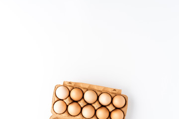 Overhead shot of chicken eggs in carton box on white table
