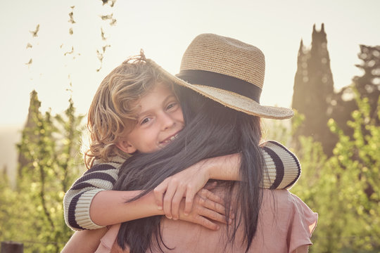 Back view of unrecognizable mom and son having fun on countryside and woman keeping son on her arms hugging