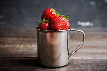 Ripe and juicy strawberries in old rustic metal cup. Selective focus. Shallow depth of field. 