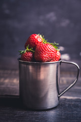 Ripe and juicy strawberries in old rustic metal cup. Selective focus. Shallow depth of field. 