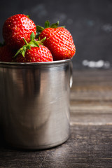 Ripe and juicy strawberries in old rustic metal cup. Selective focus. Shallow depth of field. 