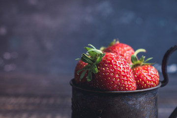 Ripe and juicy strawberries in old rustic metal cup. Selective focus. Shallow depth of field. 