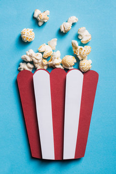 Silhouette of a stripped popcorn box made of cardboard with real popcorn on blue background