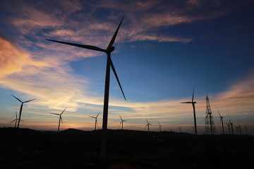 Silhouettes power generator wind turbine with sunset.