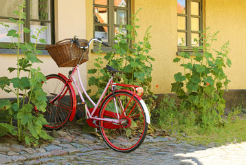Fototapeta na wymiar Red women's bicycle with a basket. Bike are parked in a bicycle rack.