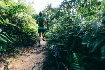 Obraz premium Woman ultra marathon runner running on tropical forest trail