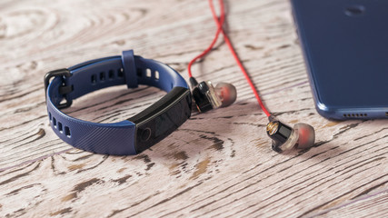 Lying on the table headphones, smartphone and smart bracelet. Sports style.