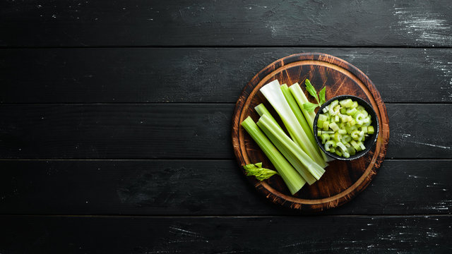 Fresh green celery stalk on a black background. Healthy food. Top view. Free space for your text.