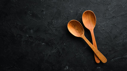 A wooden spoon on a black background. Top view. Free space for your text.