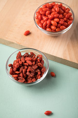 Frische und getrocknete Goji-Beeren Superfood in Glas Schale auf Holz Brett und Mint Grün Pastell Hintergrund