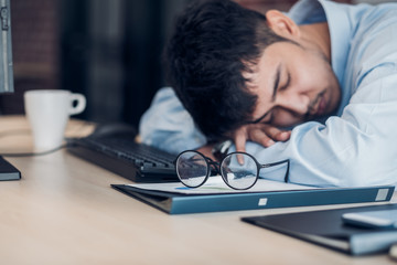 Tired asian businessman sleep on working desk table in office.working hard and late.burn out syndrome.