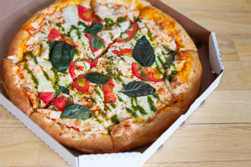 Hot tasty italian pizza with vegetables in box on wooden background