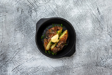 Pan of baked potatoes with butter at concrete textured table background.