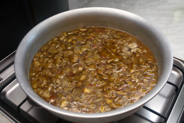 Pear jam cooked on the stove in a larger aluminum bowl