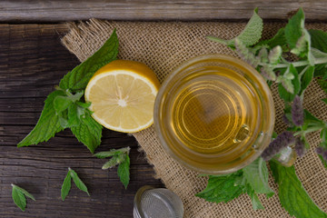 Hot peppermint tea with lemon on wooden background