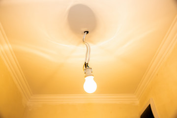 New light bulb with wires in the ceiling. Electricity maintenance repair works in the flat. Restoration indoors.