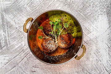 Closeup top view pan of meatballs served with sauce at concrete textured table background.
