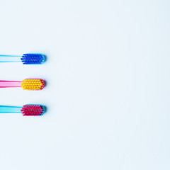 Colorful tooth brushes with bright color bristles on a light pastel blue background. Dental tools with empty space for text for  your mockup.