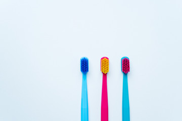 Colorful tooth brushes with bright color bristles on a light pastel blue background. Dental tools with empty space for text for  your mockup.