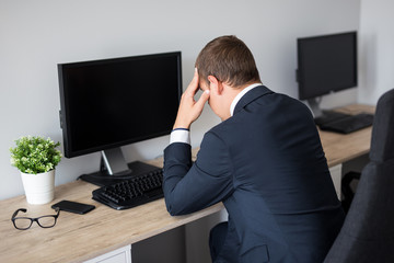 back view of stressed business man in office - blank pc screen with copy space