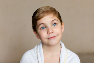 Blode caucasian boy after bath with wet hair and white towel on the head. Funny face, great smile, positive mood