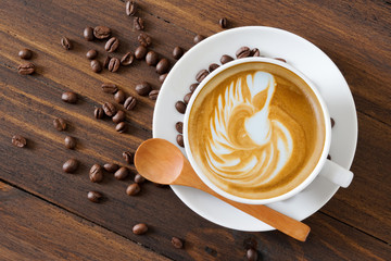 white coffee cup with latte art and roasted coffee beans around