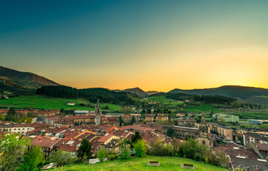 Fototapeta na wymiar City in valley with morning sunlight. Yellow and blue morning sunlight sky over the mountain. Spring season in Europe. Green grass field and pine forest in rural village on the hill. Old city in Spain