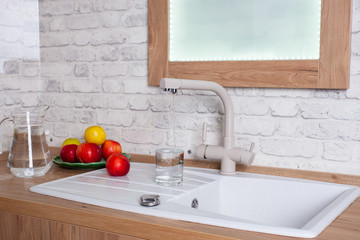 The glass is filled with tap water in the kitchen