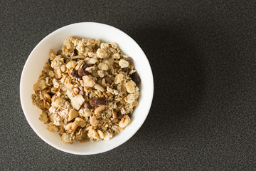 Oat flakes or Granola with nuts, dry fruit and berries on black stone table. Oat flakes as a healthy eating. Top view with copy space.