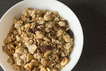Oat flakes or Granola with nuts, dry fruit and berries on black stone table. Oat flakes as a healthy eating. Top view with copy space.