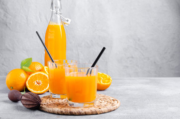 Orange juice in glass with fruits on grey  background, copy space.