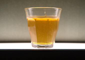 Single glass of beer sitting on a white lit surface