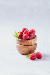 Raspberries in rustic  bowl on blue background.