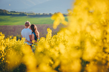 Young couple together outside in spring canola field