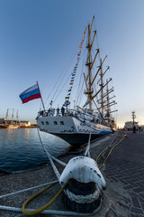 Anchor hook attached to the tall ship in the harbor at the sunset moment