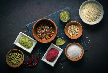 A lot of spices and seasonings in drinking bowls on a dark table. View from above.