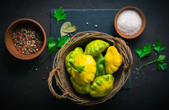 Yellow and green squash lying on a dark kitchen table. Seasonings and spices for cooking.