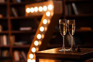 two glasses of champagne in a dark cozy room with a retro lamp