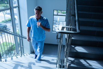 Male doctor walking upstairs on the staircase in the hospital