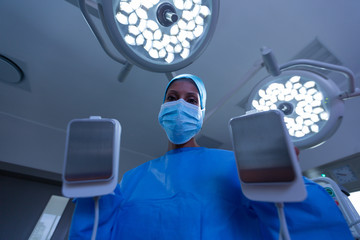 Female surgeon using defibrillator in operating room of hospital - obrazy, fototapety, plakaty