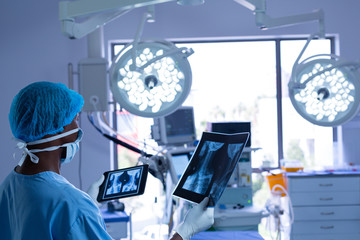 Surgeon with surgical mask examining x-ray in operating room at hospital
