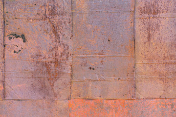 old iron wall consisting of separate pieces of metal. metal patches. Metal sheets from which the area is paint. Iron rusting.