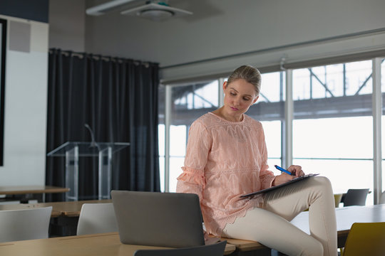 Female executive using laptop in the conference room at office