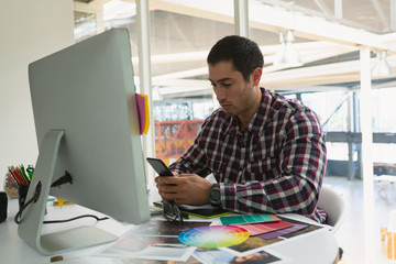 Male Graphic designer using mobile phone at desk