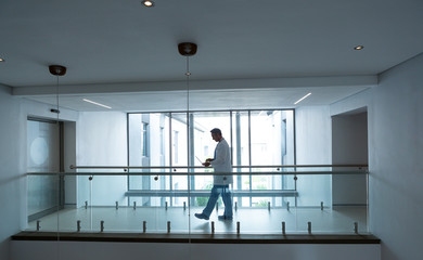 Male doctor using laptop while walking in the corridor