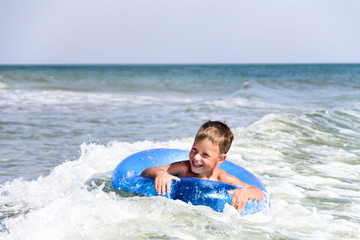 Boy riding a sea wave on inflatable ring