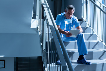 Male doctor using digital tablet on staircase in the hospital
