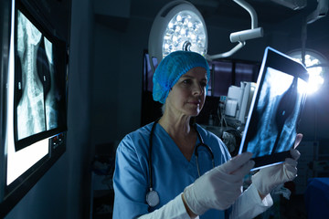 Female surgeon examining x-ray in operating room of hospital
