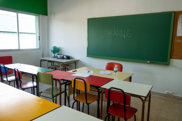 clase con mesas de colores o colegio con pizarra y mesas de colores